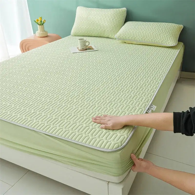 Light green quilted bed pad with gray stitched border complementing cute cartoon pattern cooling fitted sheet