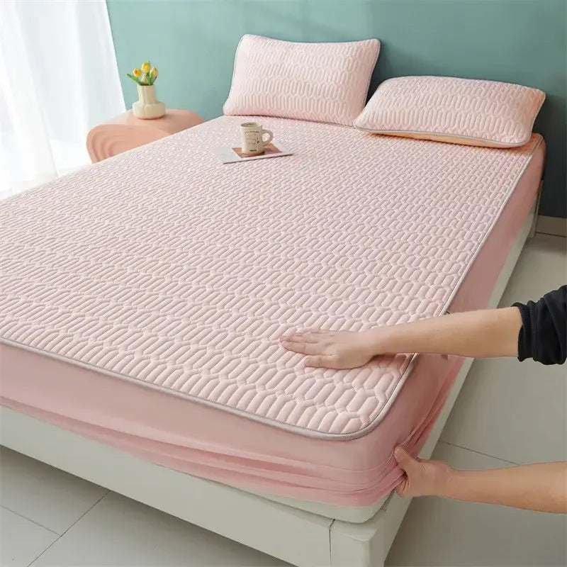Pink quilted bed pad with subtle geometric pattern and elastic edge paired with cute cartoon pattern cooling fitted sheet