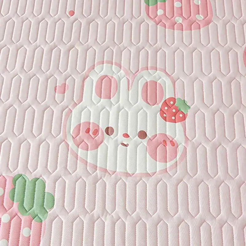 Pink quilted fitted sheet with cute cartoon pattern featuring a white bunny with pink polka dots and strawberry accents