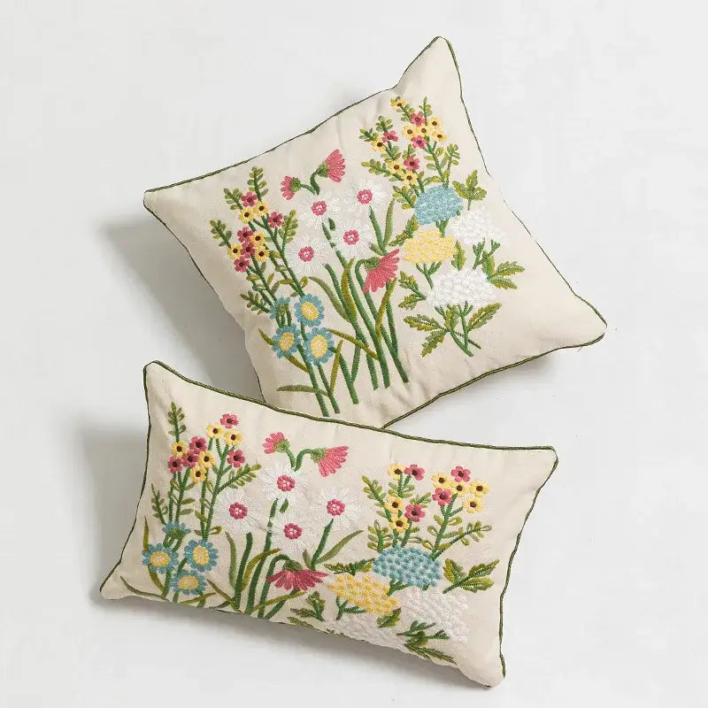 Cream-colored pillow cover with daisy floral embroidery featuring vibrant pink yellow blue and green decorbites design