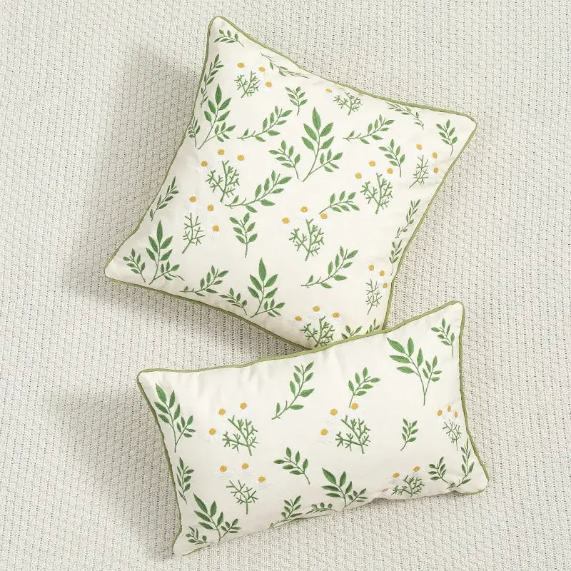 Cream-colored decorbites daisy floral cushion cover with green leaves and yellow dots framed by olive-green trim