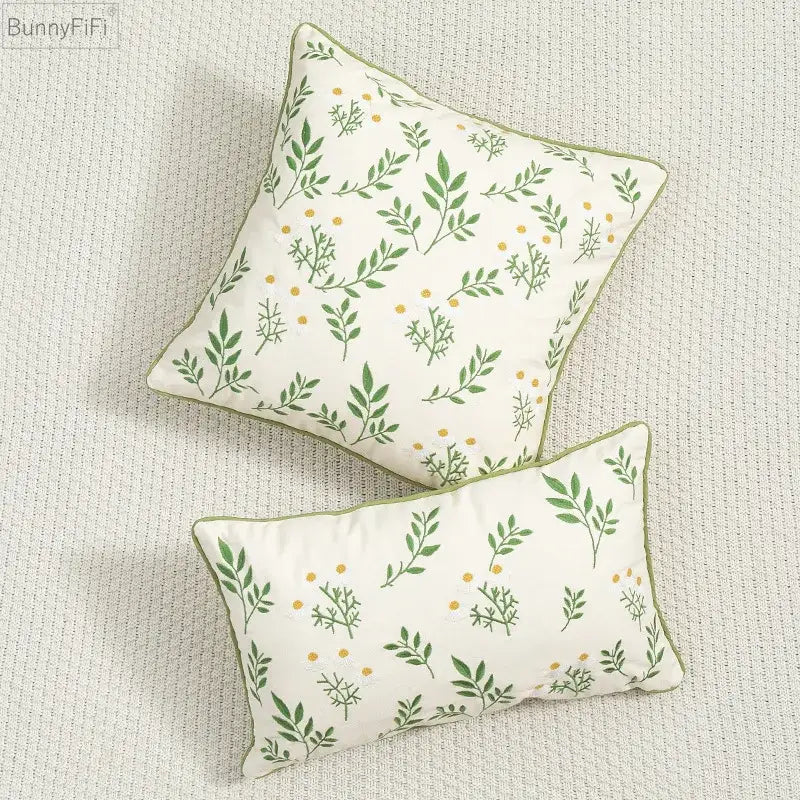 Cream-colored cushion cover with green leaves and yellow dot embroidery bordered in olive green decorbites daisy floral