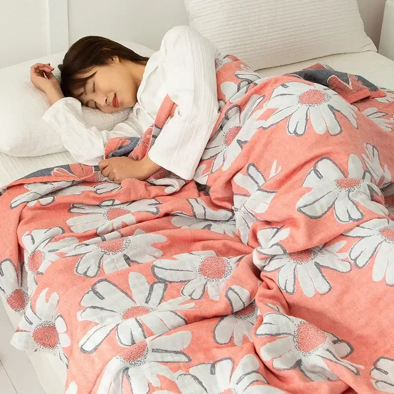 Coral-colored double cotton blanket with white daisy pattern and gray outlines made of soft plush material