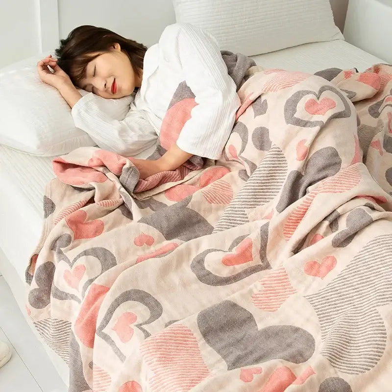 A soft pastel pink and gray heart patterned double cotton blanket with plush textured fabric for bedroom use