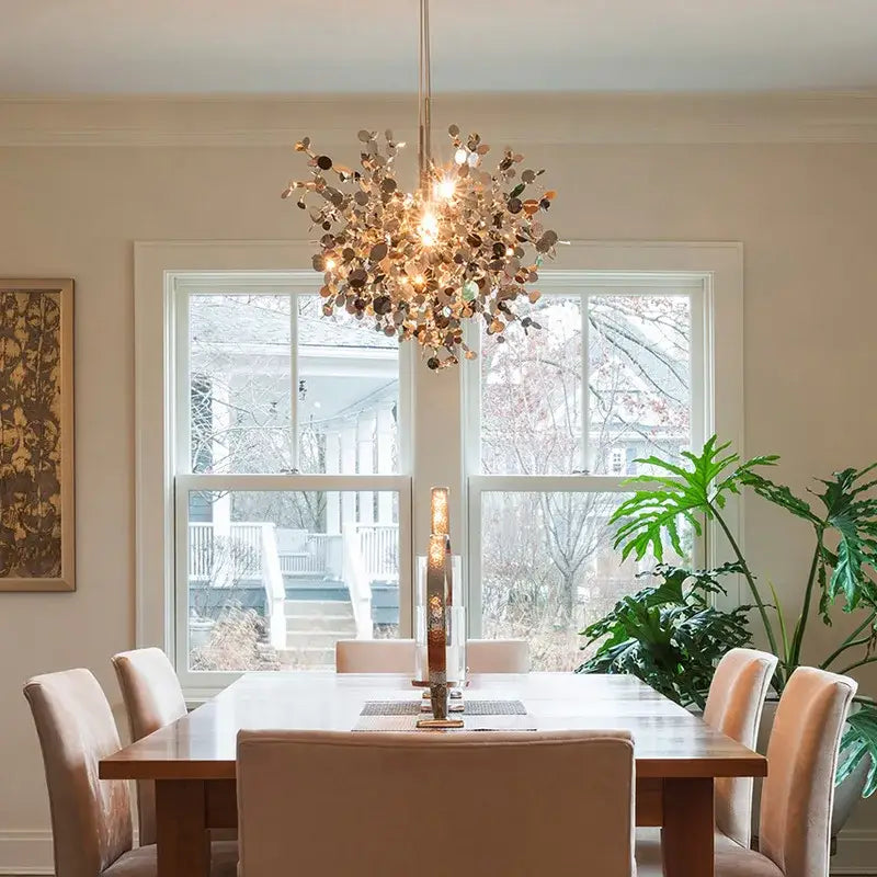 A golden leaf led chandelier with chrome leaf design hangs above a dining table for decorbites chrome leaf lighting