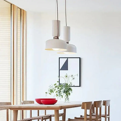 Modern white ceramic pendant light with cylindrical shades and black wrought iron cords above wooden dining table