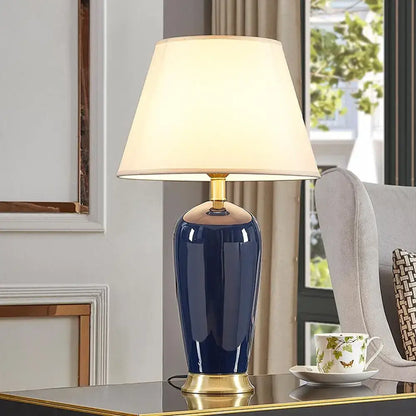 Dark blue ceramic table lamp with remote control, gold-toned base, and cream fabric shade by decorbites for bedroom decor