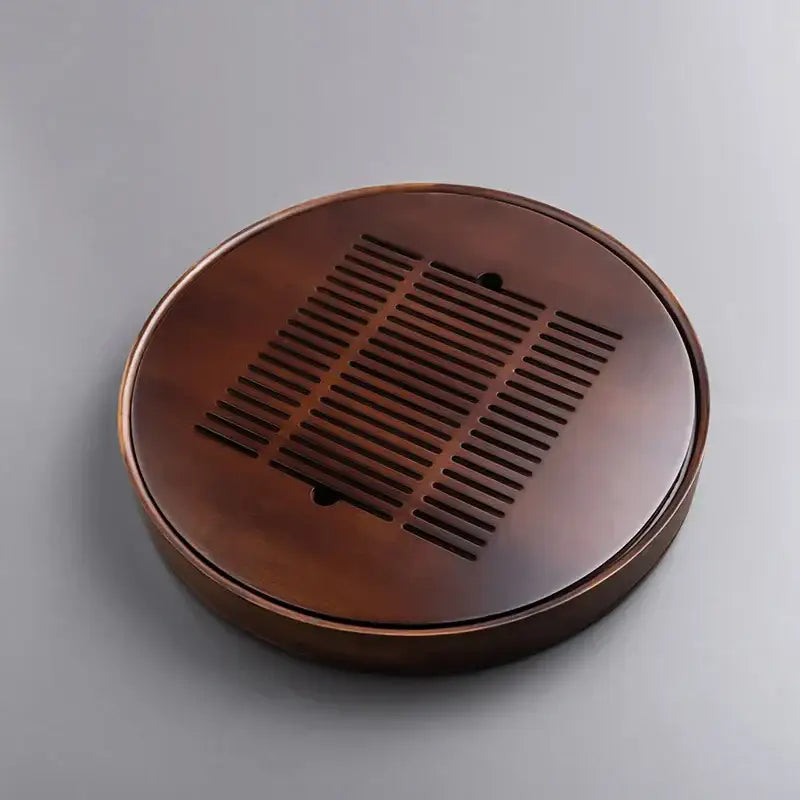 Dark brown bamboo tea tray with a circular design and central slatted drainage for kung fu tea dining room use
