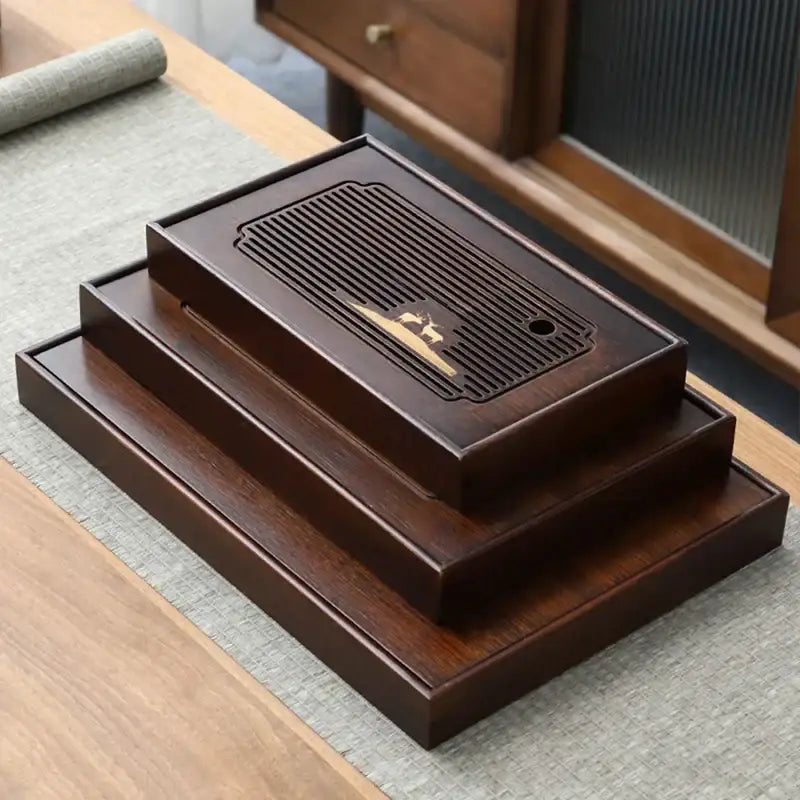 Dark brown bamboo tea tray with gold inlay and vertical slats for tea tray drainage in kung fu tea dining room use