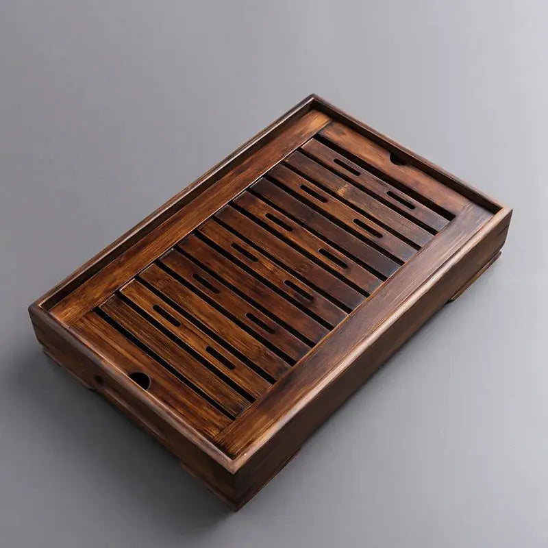 Dark brown bamboo tea tray with slatted surface and raised edges for kung fu tea drainage in dining room