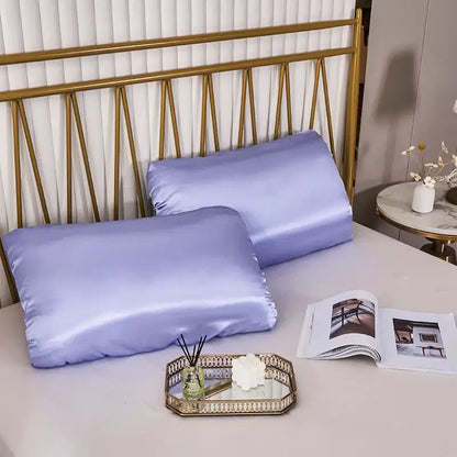 Two lavender satin pillowcases with elastic band on bed with gold headboard dark gray decorbites imitation silk elastic