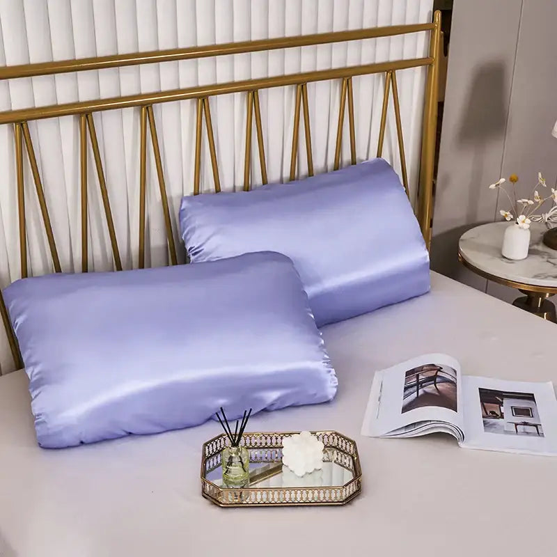 Two lavender satin pillowcases with elastic band on bed with gold headboard dark gray decorbites imitation silk elastic