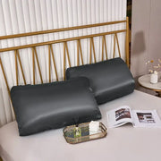 Two dark gray imitation silk elastic band pillowcases on bed with gold-toned headboard for bedroom decorbites bedding