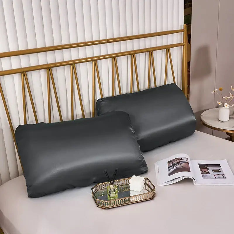 Two dark gray imitation silk elastic band pillowcases on bed with gold-toned headboard for bedroom decorbites bedding