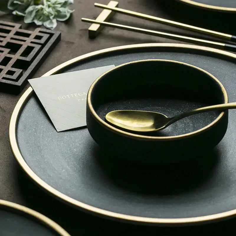 Black ceramic bowl with gold rim and matching gold spoon from decorbites ceramic western dinnerware set for dining room use