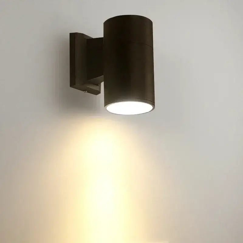 Dark bronze cylindrical 10w light wall sconce with sleek modern design casting warm light downward for outdoor use