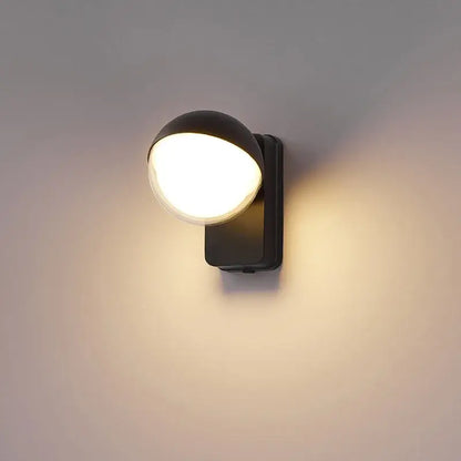 Modern black spherical wall lamp with motion sensor emitting warm diffused glow for porch lighting