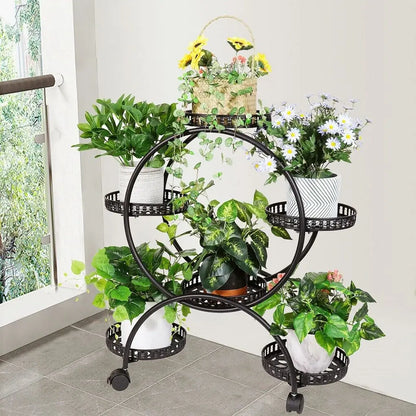 Black wrought iron decorbites plant stand shelf with decorative perforated tiers and caster wheels holding six pots