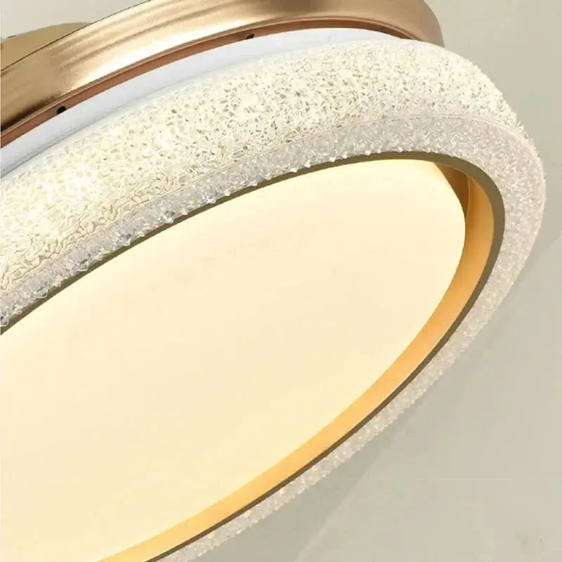 Gold-toned retractable ceiling fan light with textured crystal ring and frosted glass diffuser for bedroom use