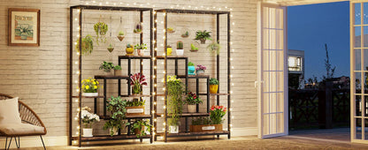 Black metal decorbites™ 5-tier tall plant stand with hanging hooks featuring string lights and assorted potted plants