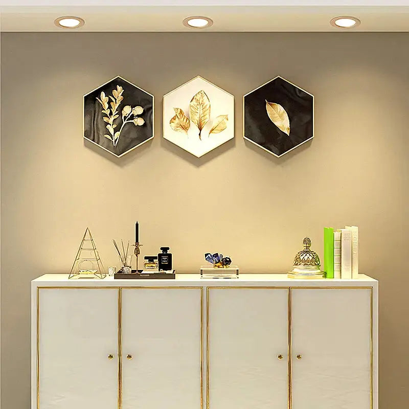 Three hexagonal wall art pieces with gold leaf designs featuring metallic frames complement gold led ceiling downlight decor