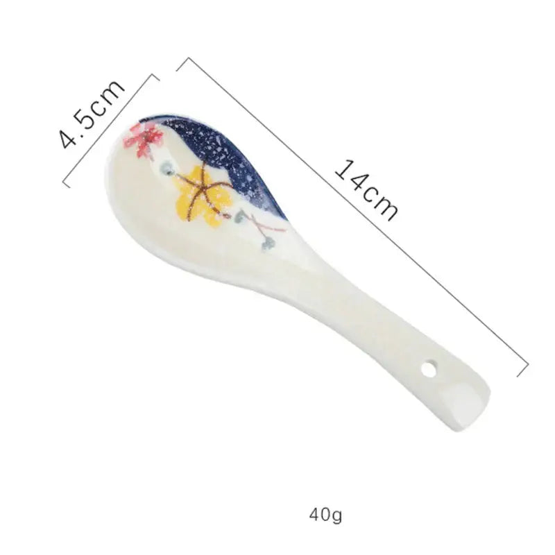 A delicate white ceramic spoon rest with hand-painted floral and star design complements the ceramic ramen bowl design