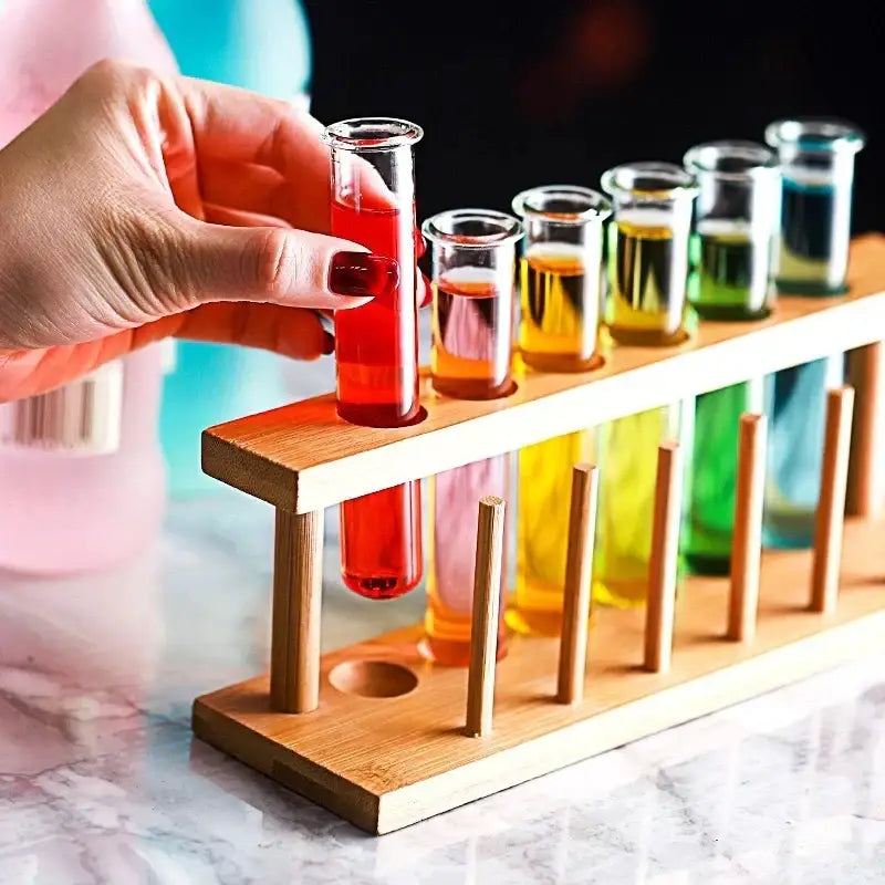 A wooden rack holding clear glass tubes filled with colorful liquids in the decorbites™ test tube cocktail glass set