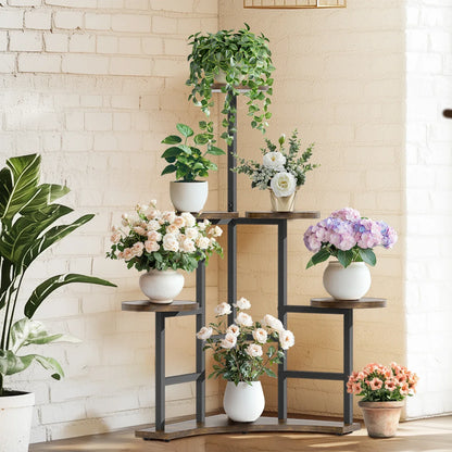 Black metal corner plant stand with wooden shelves holding white ceramic pots and floral arrangements by DecorBites™
