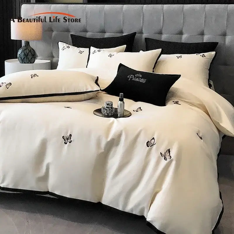 Cream-colored satin bedding set with black butterfly embroidery and contrasting piping in 600tc egyptian cotton