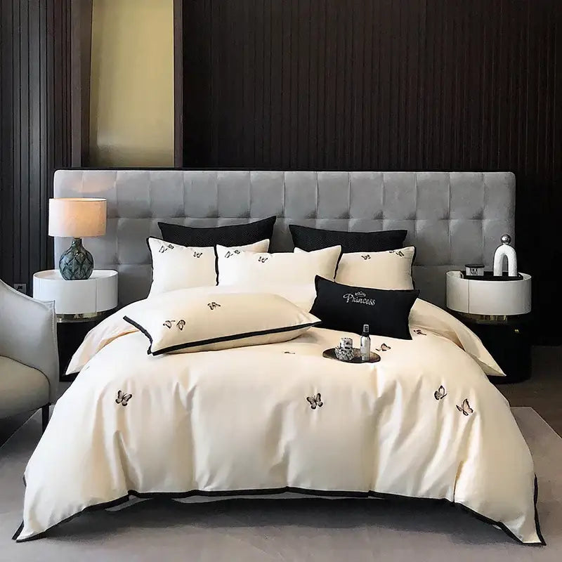 Cream-colored satin duvet set with black butterfly embroidery and piping made from 600tc egyptian cotton by decorbites