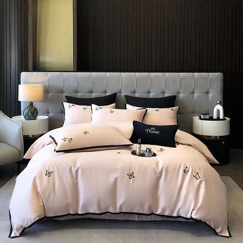 A blush pink satin bedding set with black butterfly embroidery and trim made of 600tc Egyptian cotton by DecorBites
