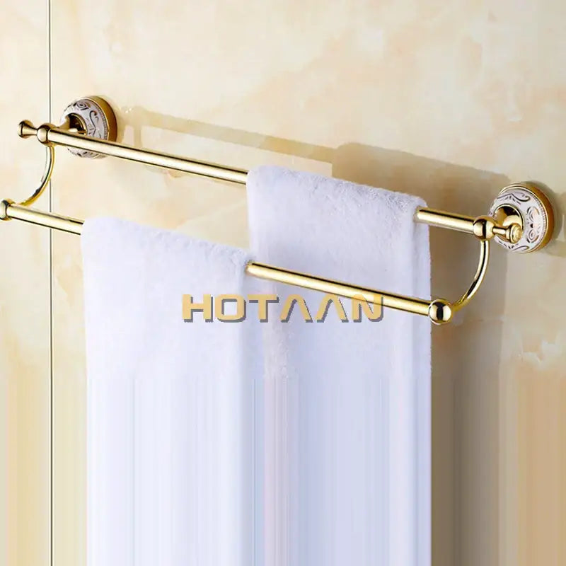 Decorbites 60cm double towel bar with ceramic gold finish features ornate circular mounts and holds white towels