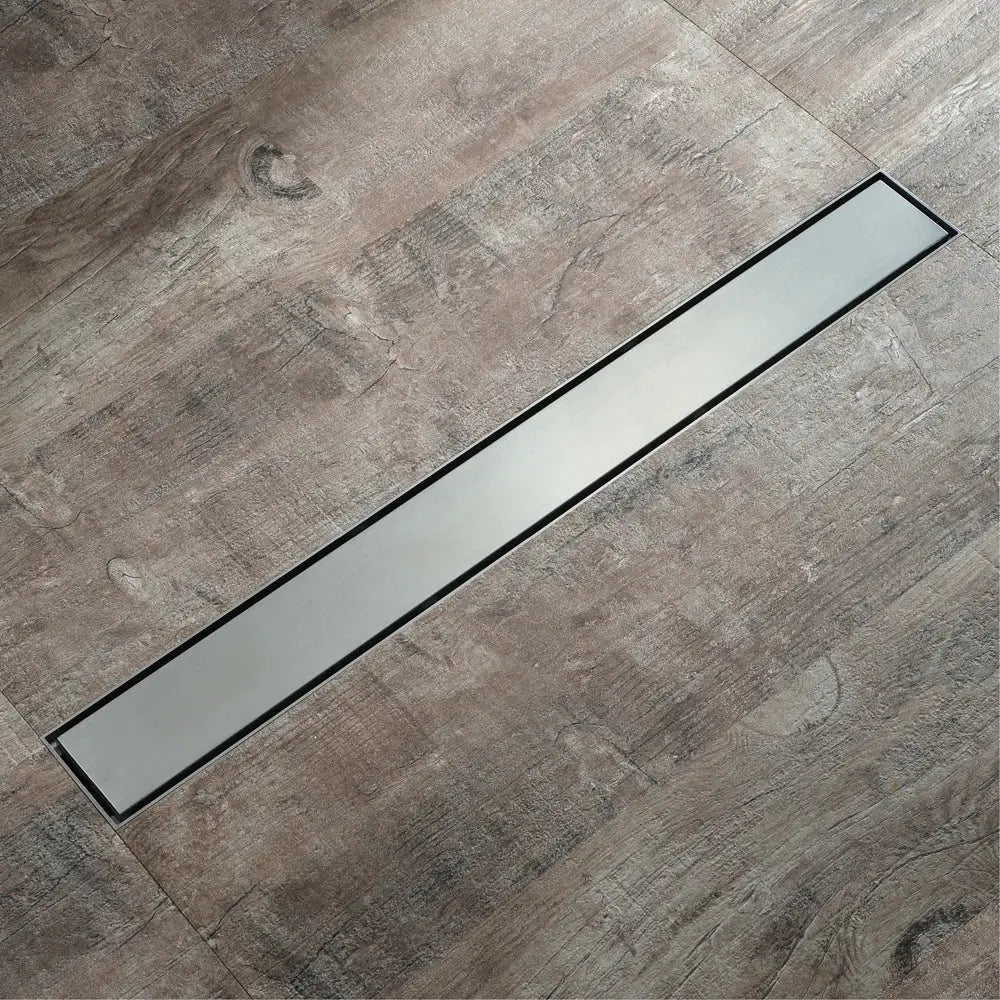 A sleek stainless steel floor drain with black trim set in gray wood flooring for decorbites 60cm rose gold bathroom use