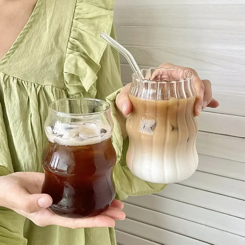 Two clear glass tumblers with wavy ribbed sides hold dark iced coffee and creamy iced latte with transparent straws in 650ml latte ribbed set