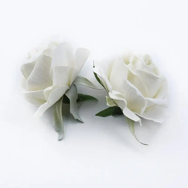 Two artificial white roses head with delicate layered petals and soft green leaves for home and wedding decor