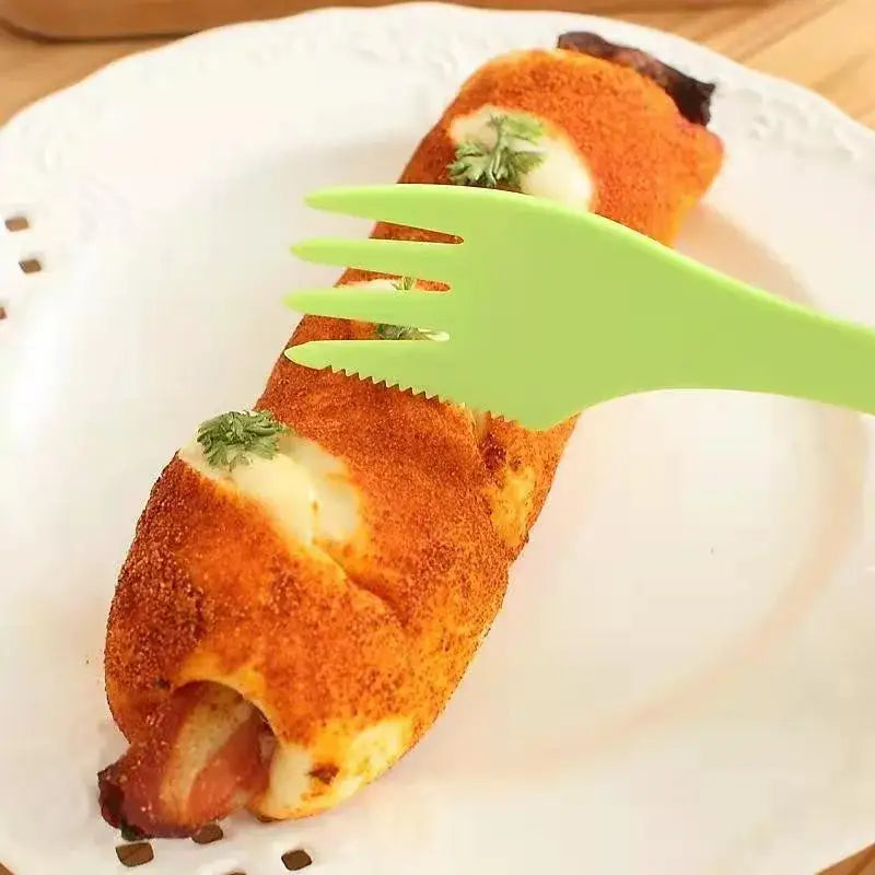 Bright green plastic fork with serrated tines from decorbites 6pcs outdoor spork set resting on a golden brown bread roll