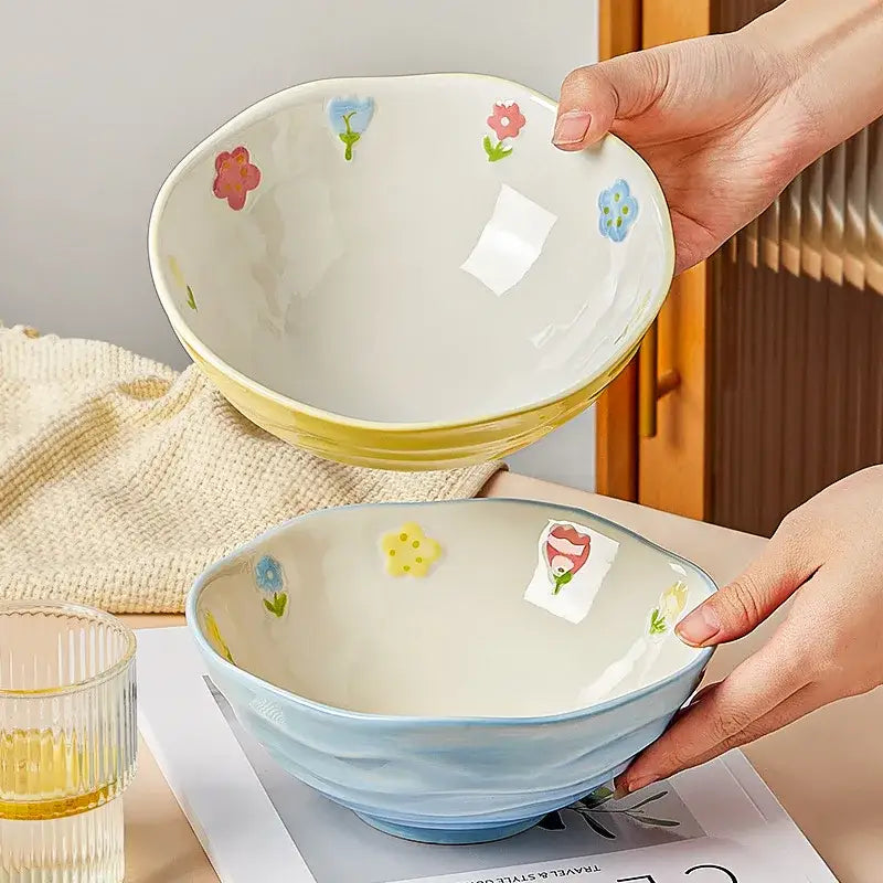 A decorative ceramic ramen bowl with a soft yellow rim and pink blue green floral decals for home and restaurant use