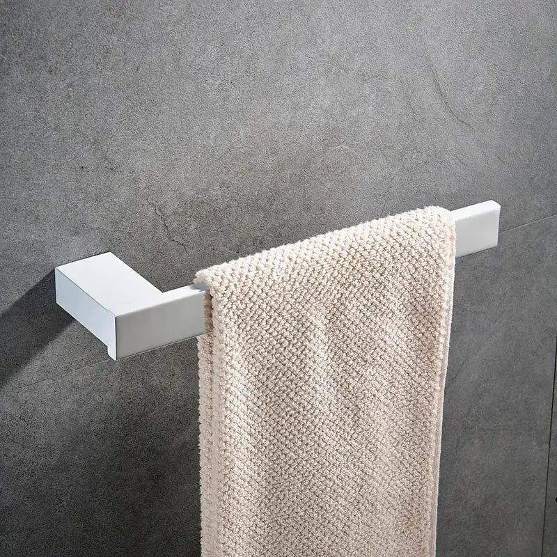 White rectangular towel rack holding a cream textured towel from the DecorBites bathroom hardware set in white
