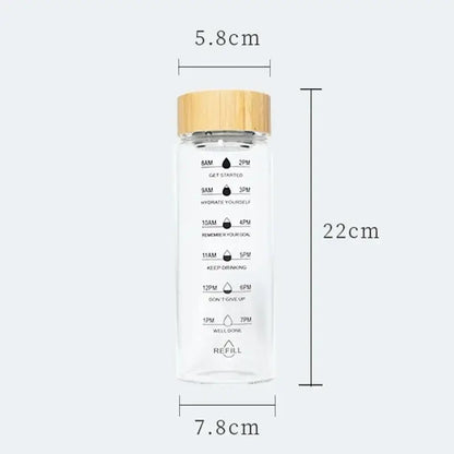 Clear glass water bottle with bamboo lid and measurement markings for hydration tracking from DecorBites™