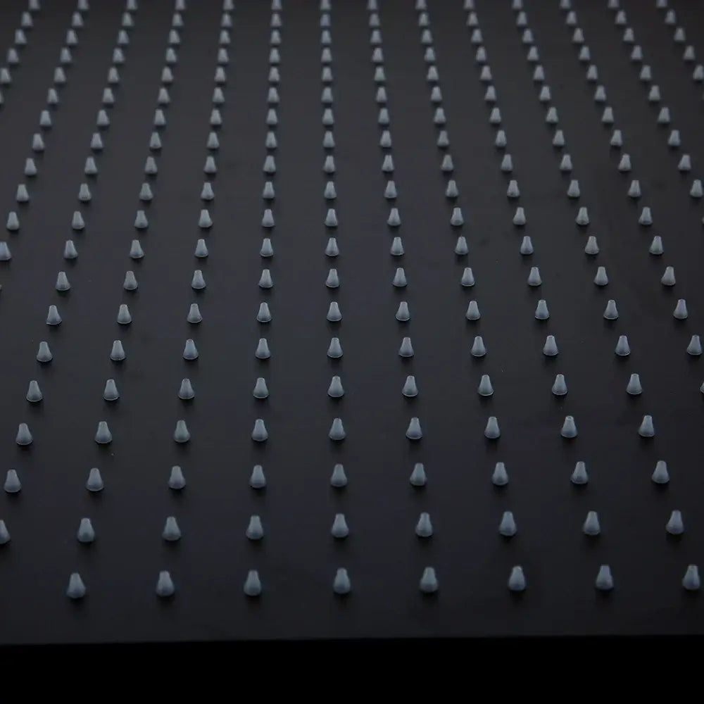 Rows of uniform white plastic spikes embedded in a black ultra-thin rain shower head surface for bathroom use