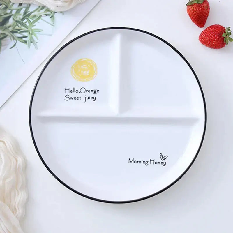 White ceramic round grid plate with black rim and three compartments featuring orange illustration for solo dining