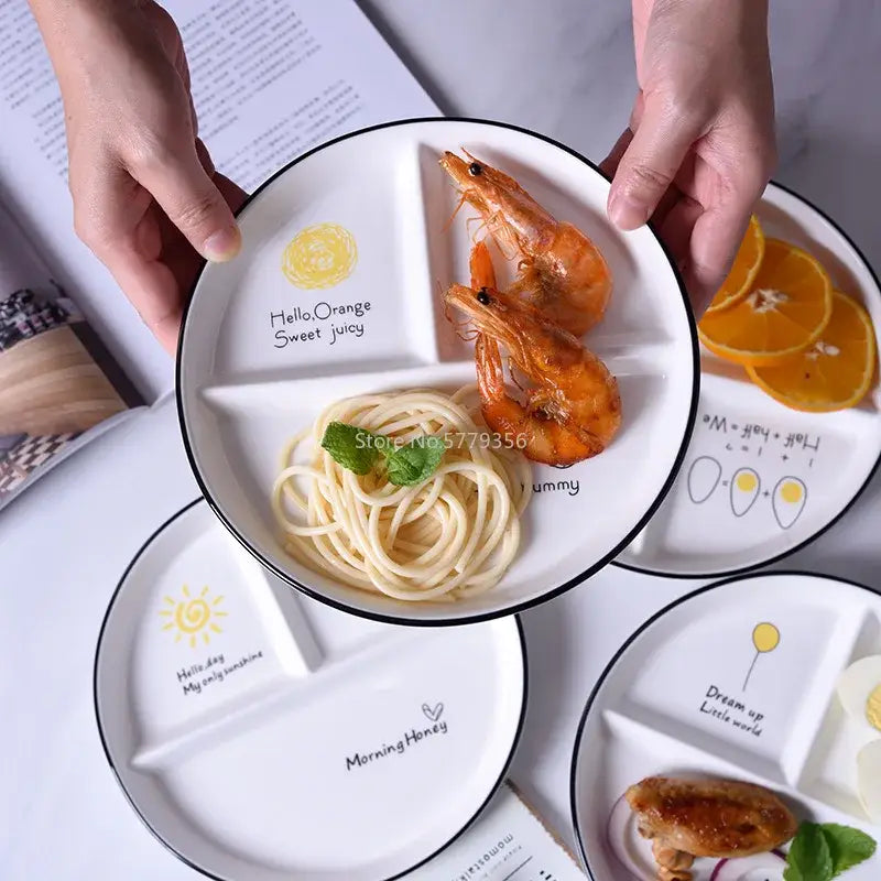 White ceramic DecorBites™ round grid plate with black rim and playful food-themed illustrations for children