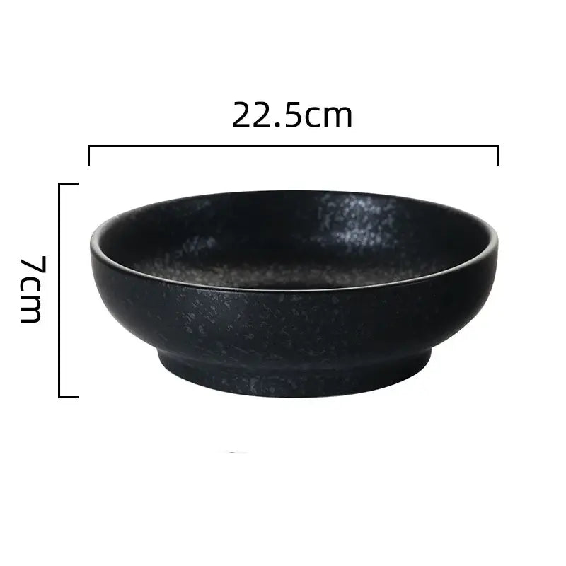 A sleek matte black retro ceramic ramen noodle bowl with speckled texture and rounded edges for soup and pickled cabbage