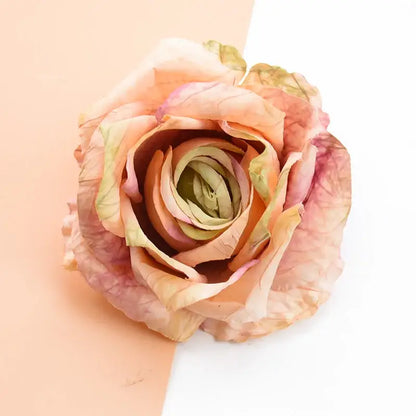 A delicate peach and blush pink 9cm silk roses artificial flowers with subtle green undertones for home decor and weddings