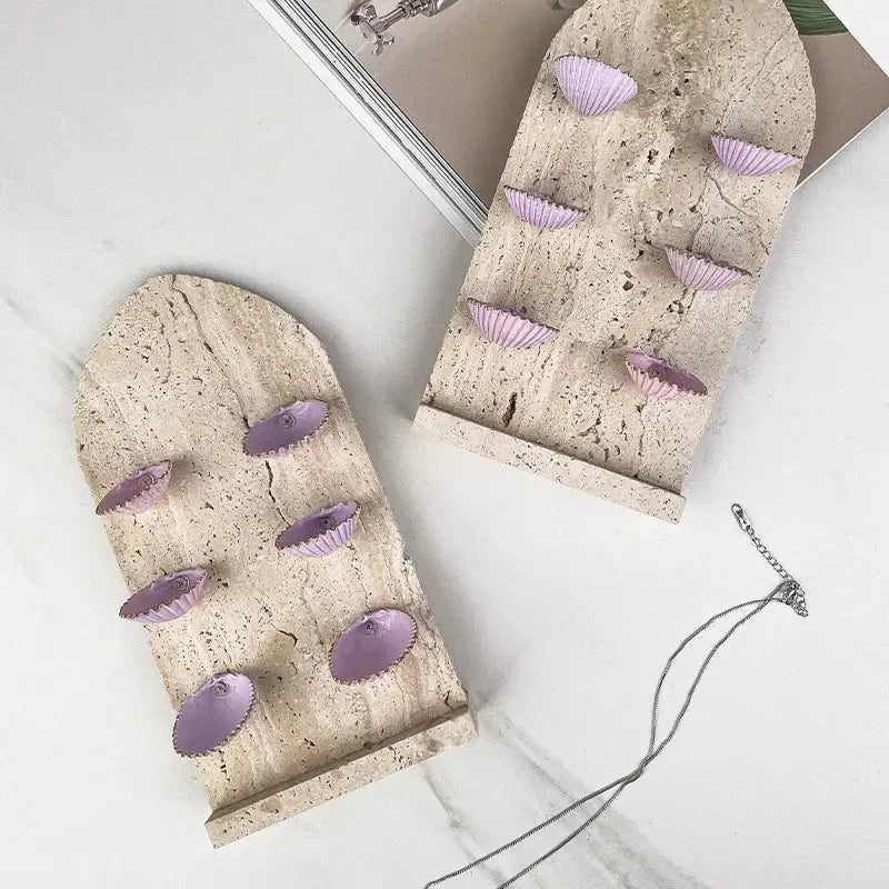 Two arched beige stone jewelry organizers with lavender abalone shell-shaped indentations decorbites abalone shell