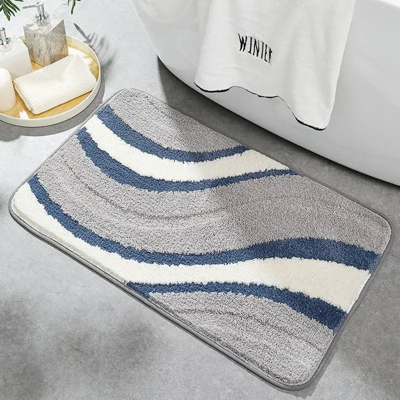 A plush decorbites absorbent water bathroom mat with navy blue and off-white wavy stripes on a soft gray base