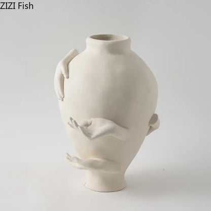Cream-colored decorbites abstract art ceramic vase with sculpted hands wrapping its rounded body for desk decoration