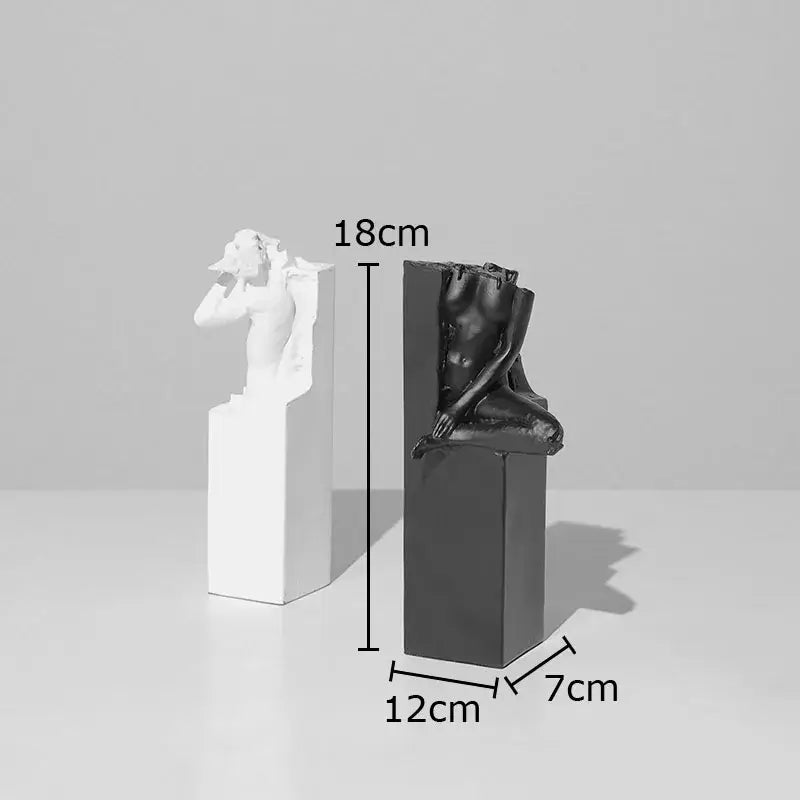 Two minimalist resin character statues in white and black depicting abstract sculpting oneself artworks on pedestals
