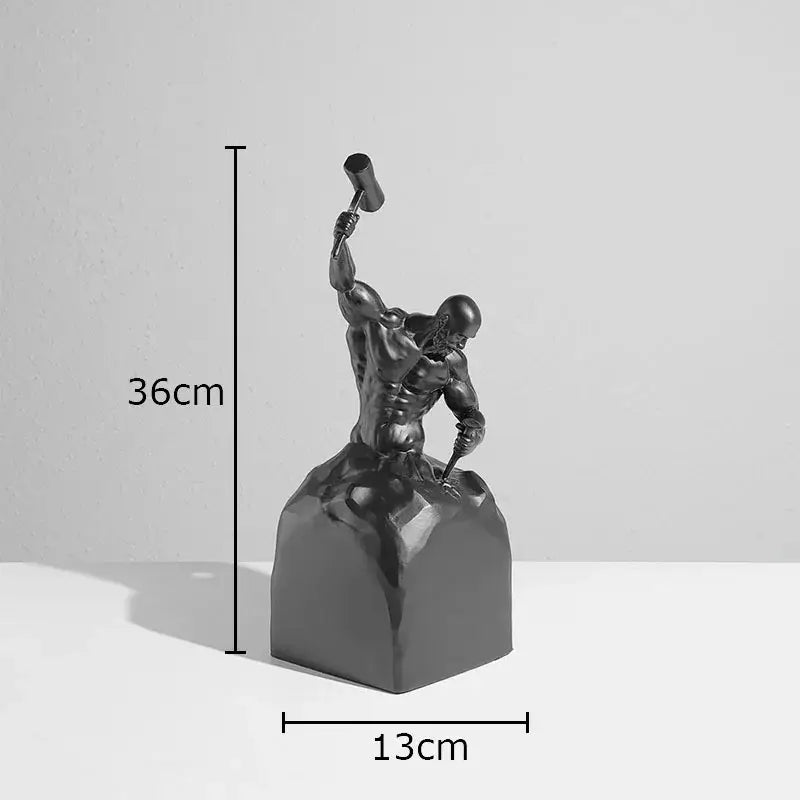 Black metallic resin character statue of a muscular man wielding hammer seated atop block for desk ornament