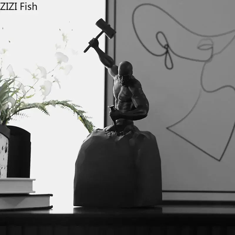 Black resin character statue of a muscular figure holding a hammer seated on a rock base decorbites abstract art sculpture